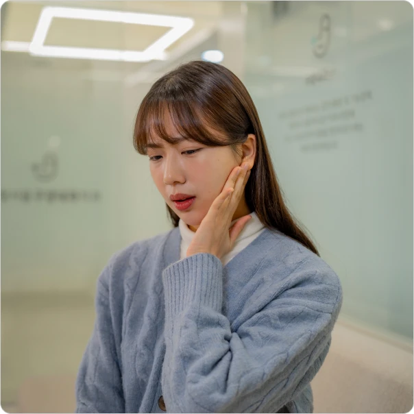 턱 옆을 손으로 짚으며 통증을 호소하는 환자