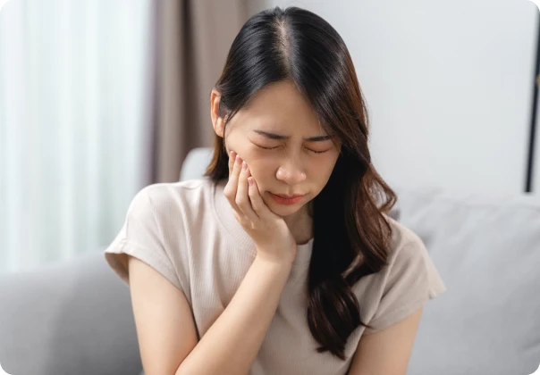 소파에 앉아 턱 통증을 호소하는 여성