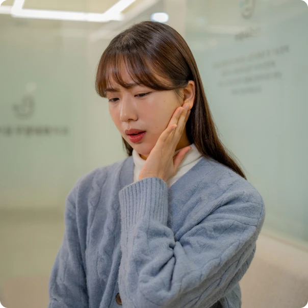 턱을 감싸 쥐고 통증을 참는 환자