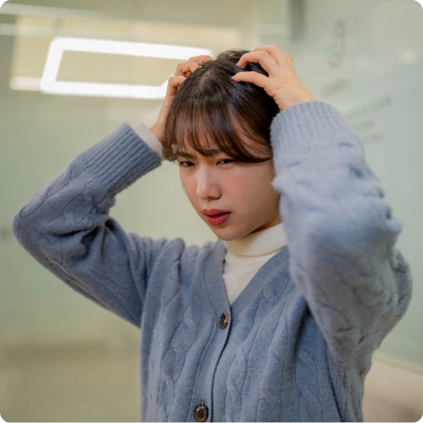 두 손으로 머리를 감싸 쥐고 괴로워하는 여성