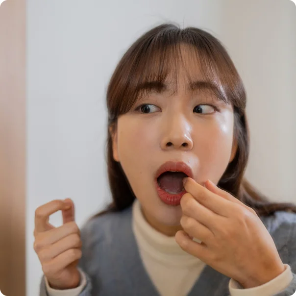 거울을 보며 입술 안쪽 병소를 확인하는 여성