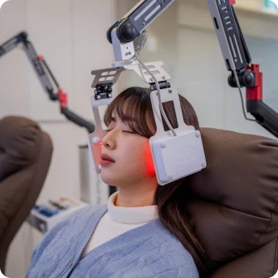 레이저 치료 장비를 얼굴에 맞추고 누워 있는 환자