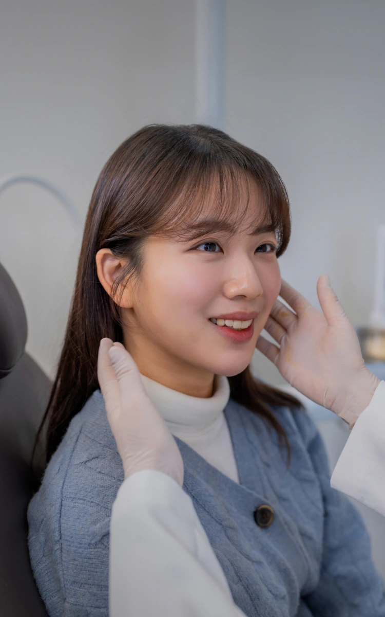 시청서울구강내과 진료 의자의 환자 턱 부위를 촉진하는 원장